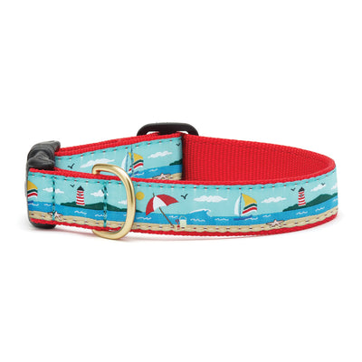 Up Country Inc Coastal Dog Collar Shows ribbon dog collar with coastal seaside including sailboat lighthouse umbrella ocean and sand on red webbing